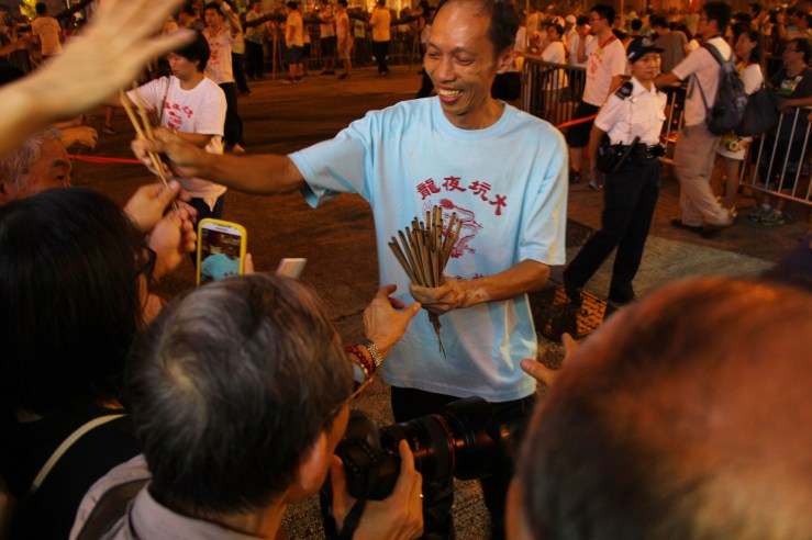 Man hands out joss sticks to the crowd. | Tai Hang Fire Dragon Dance, Tai Hang, Hong Kong | September 27, 2015 | Tanya McGovern
